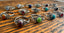 Handcrafted sterling silver gemstone rings in a rainbow of colours on a wooden table