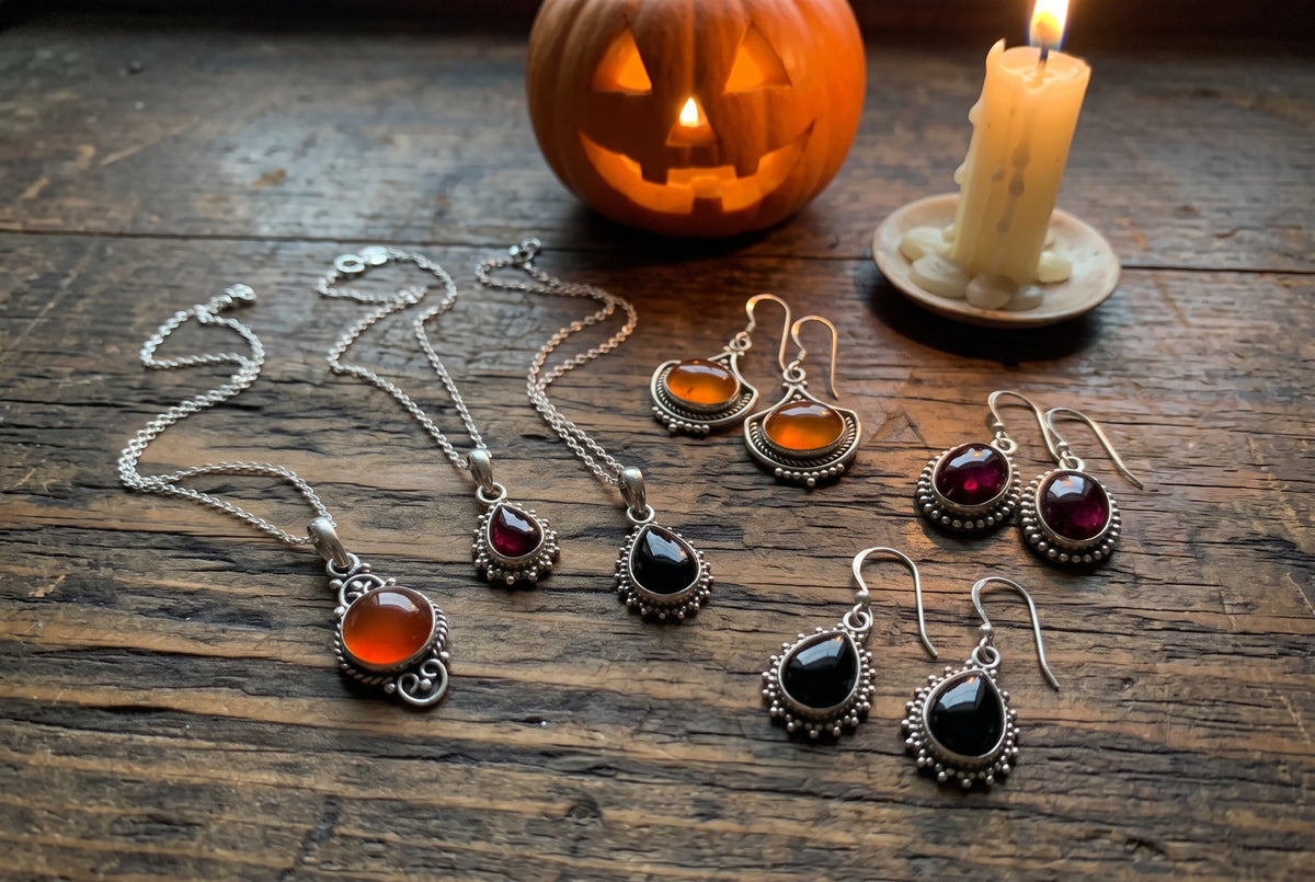 Springwaves carnelian, garnet and black onyx sterling silver pendants and earrings on an old wooden bench by a glowing jack-o'-lantern